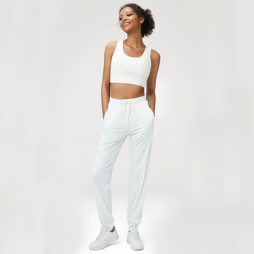 Woman wearing a stylish white joggers and sports bra set, featuring adjustable drawstrings and breathable fabric, perfect for versatile wear.